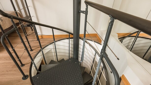 Eine Wendeltreppe mit Metallgeländern und einem Boden in Rautenmuster.