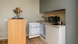 Una cuina compacta amb microones integrat, un rentat petit i un frigorífic.