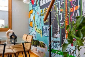 A modern interior with a glass table, leather chairs, and a colorful graffiti wall. - Studio with a mezzanine (Kraków - Kazimierz & Podgórze)