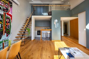 A modern interior with a staircase, kitchen, dining area, and books on a table.