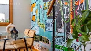 A modern interior with a glass table, leather chairs, and a colorful graffiti wall.