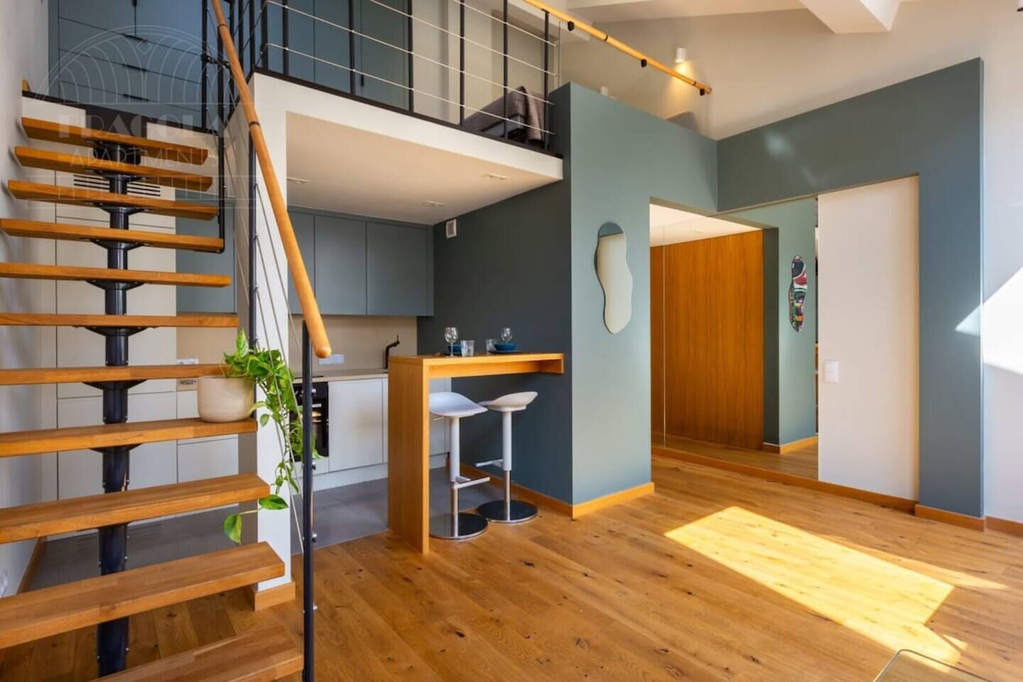 A modern apartment with a wooden staircase, a kitchen with a dining area, and a large window.