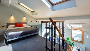 A bedroom with a skylight, a bed, a desk, and a chair. - Studio with a mezzanine (Kraków - Kazimierz & Podgórze)