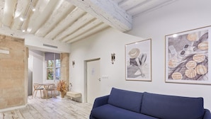 Un soggiorno moderno con un divano blu, pavimento in legno e opere d'arte alle pareti.