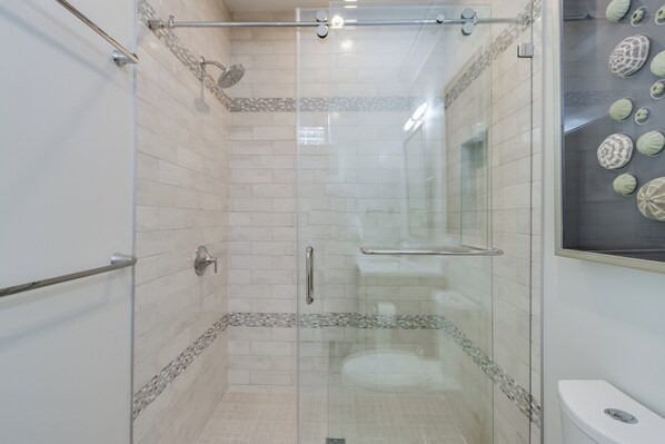 A modern bathroom with a glass-enclosed shower, tiled walls, and a toilet.
