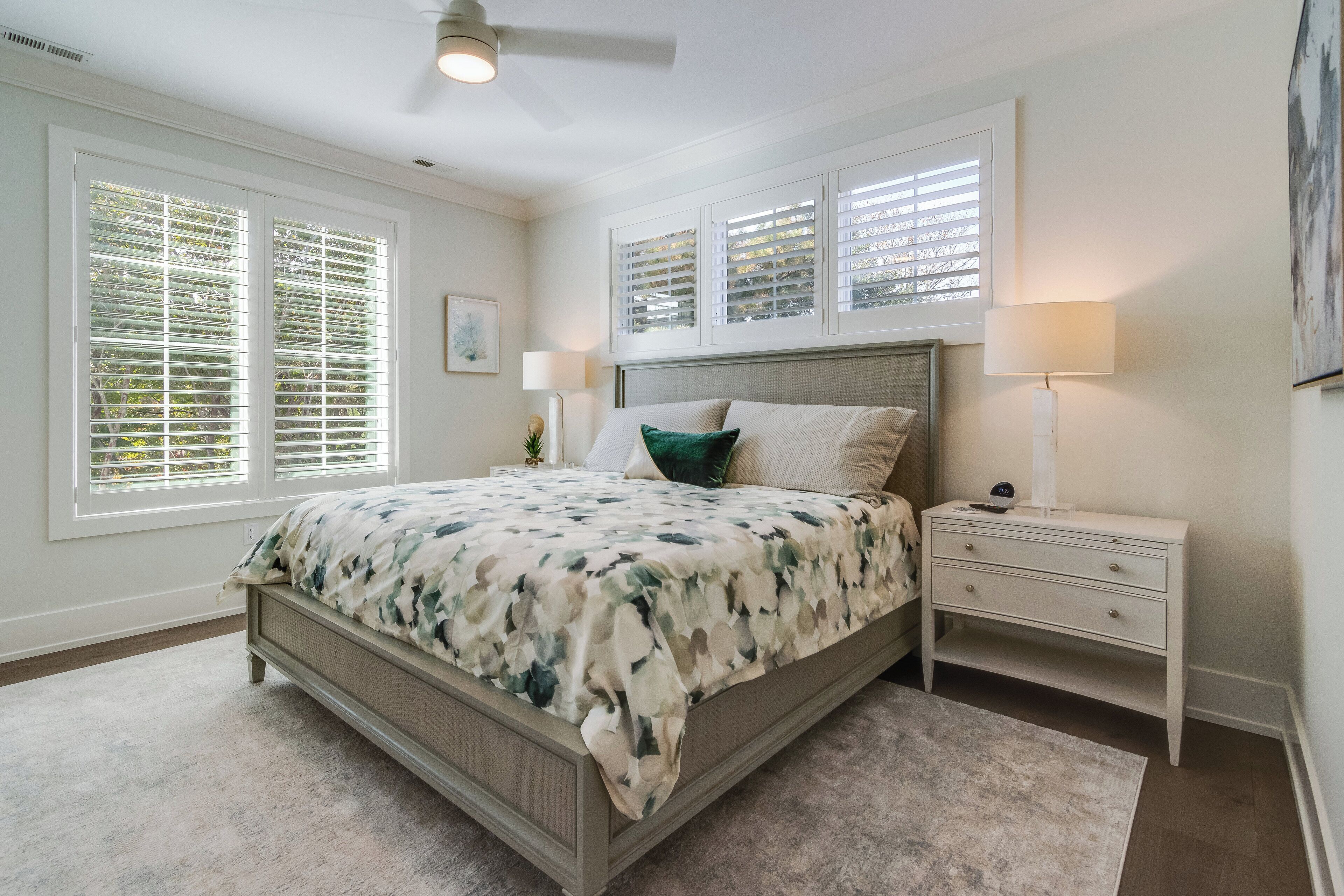 A bedroom with a bed, nightstands, a lamp, and a ceiling fan.