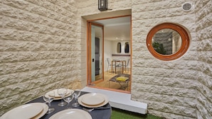 A dining area with a table set for four, a glass door leading to a dining room, and a round mirror on the wall. - Charming Apartment Faubourg St Honore Madeleine (Paris)