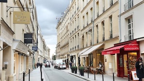 A street view with buildings, a café, and a white van parked on the side. - Charming Apartment Faubourg St Honore Madeleine (Paris)