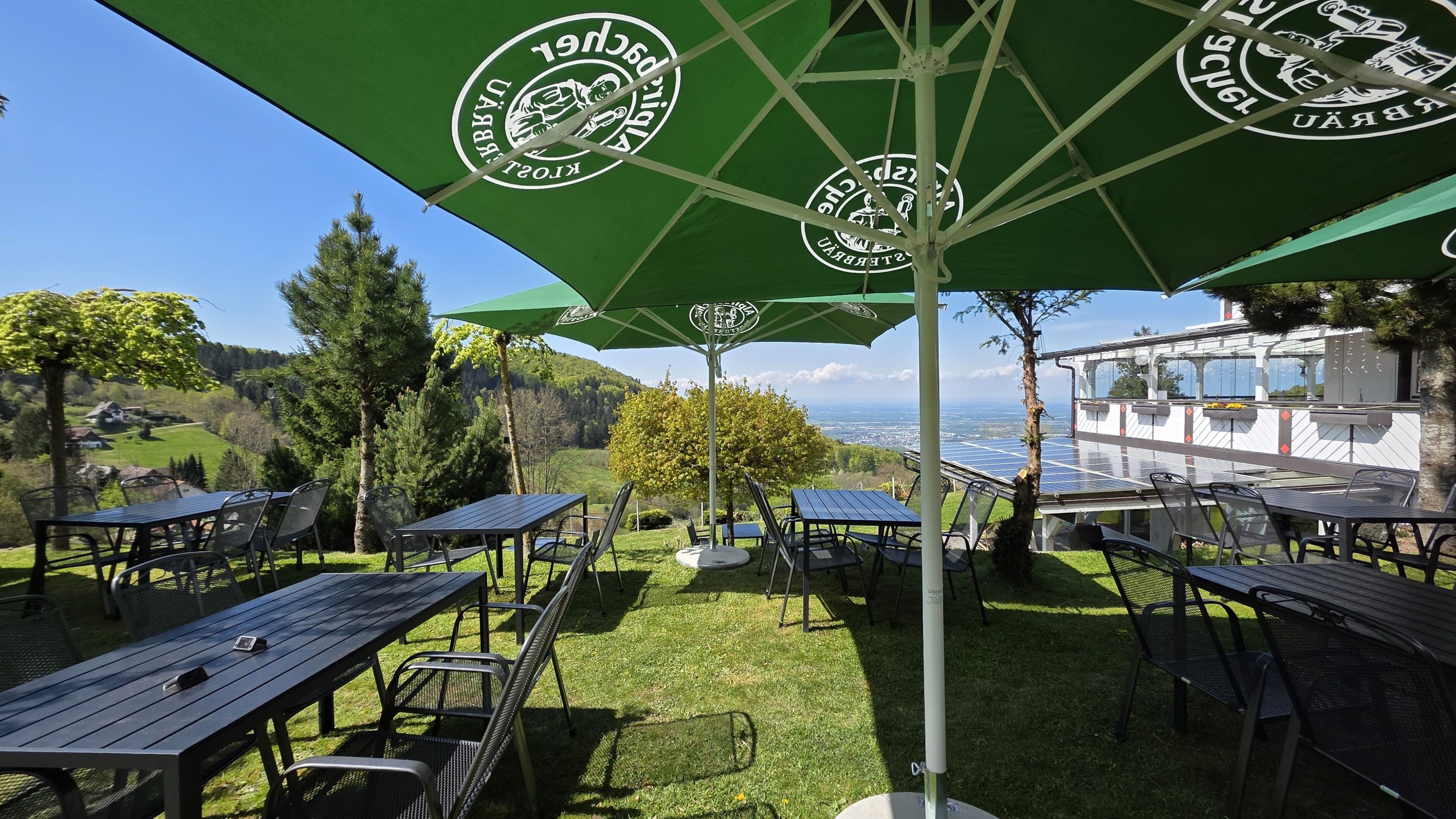 Terraza al aire libre con sombrillas, vistas al campo y paneles solares.