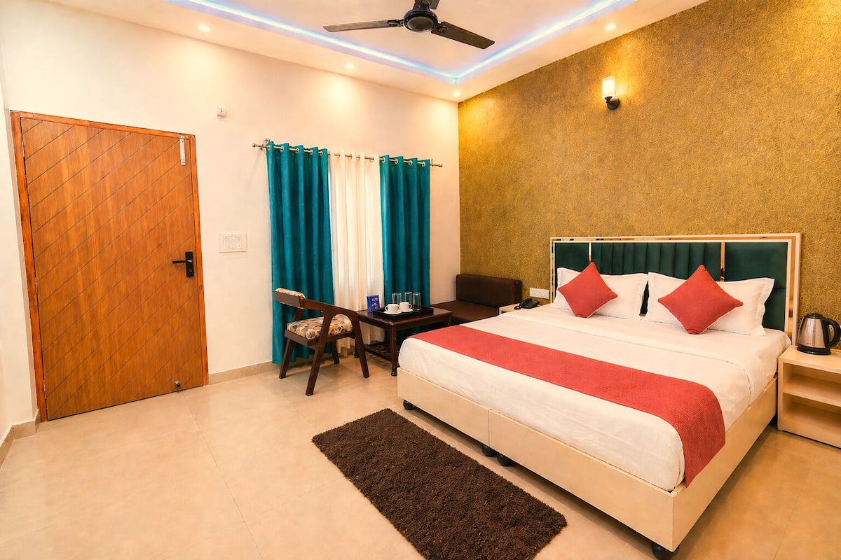 Une chambre d’hôtel comprenant un lit, un bureau, une chaise, un ventilateur de plafond et un mur orné d’un motif texturé.