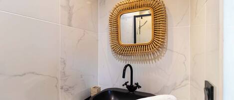 A bathroom with a black sink, a white countertop, and a mirror with a wooden frame.