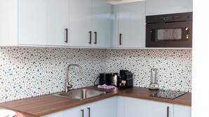 Eine Küche mit hellblauen Schränken, einer Edelstahl-Spüle, einer Kaffeemaschine und einem Mixer.