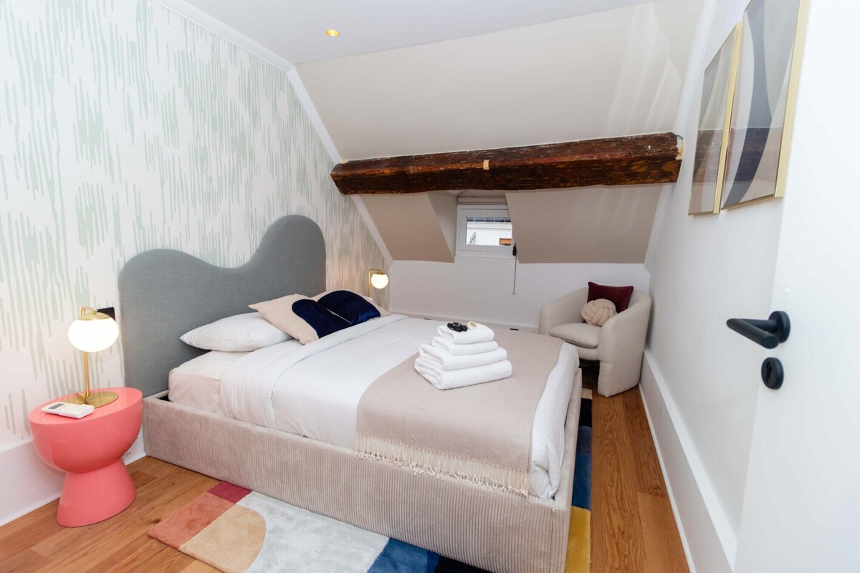 A bedroom with a bed, bedside table, chair, and a window.