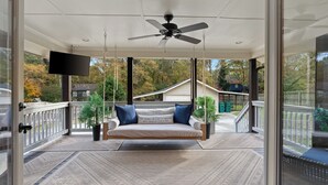 A covered porch with a swing, a ceiling fan, and a TV mounted on the wall. - Beautiful 3 bedroom ranch home in Smyrna near the Braves stadium  (Smyrna)