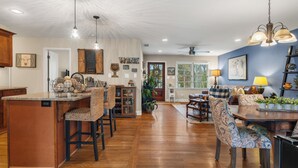 A spacious kitchen with a central island, wooden bar stools, and a dining area with patterned chairs. - Beautiful 3 bedroom ranch home in Smyrna near the Braves stadium  (Smyrna)