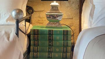 Une chambre avec deux lits, une table de chevet avec une lampe et une pile de livres verts.