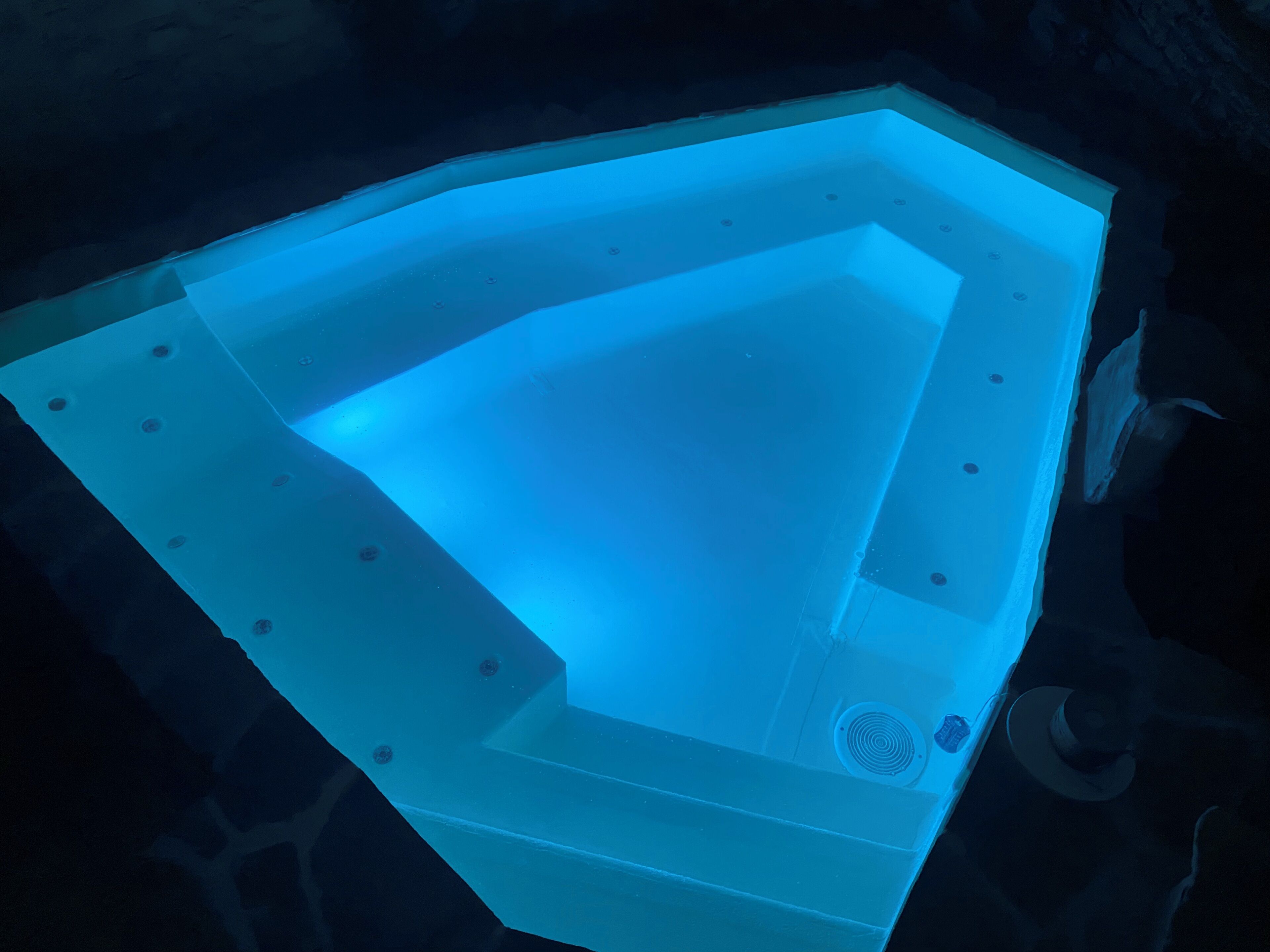 Un jacuzzi con diseño geométrico, rodeado de muros de piedra oscura.