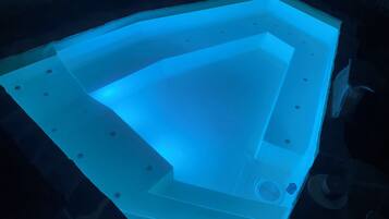 Un jacuzzi con diseño geométrico, rodeado de muros de piedra oscura.