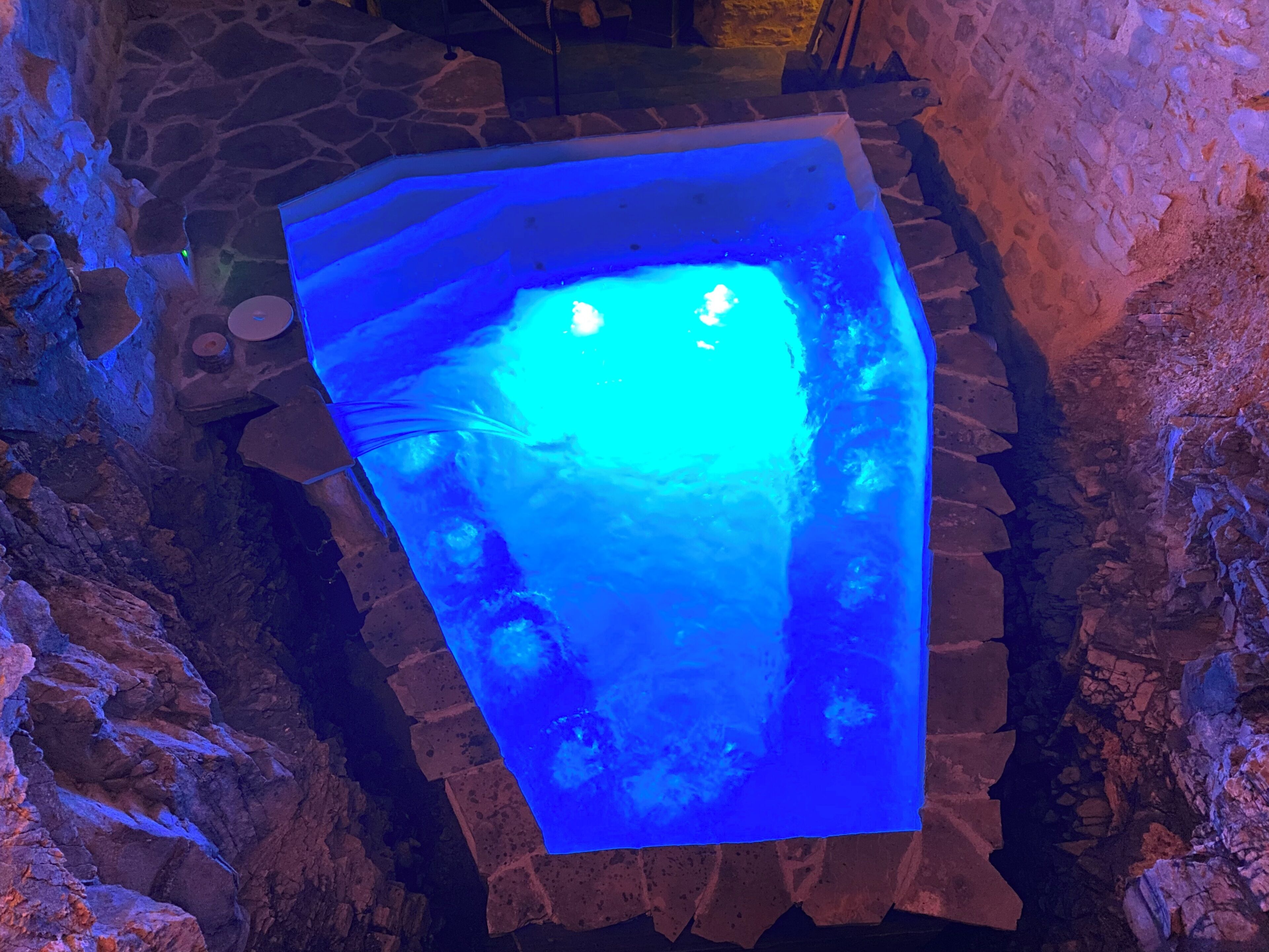 A stone-walled pool with a blue illuminated centerpiece.