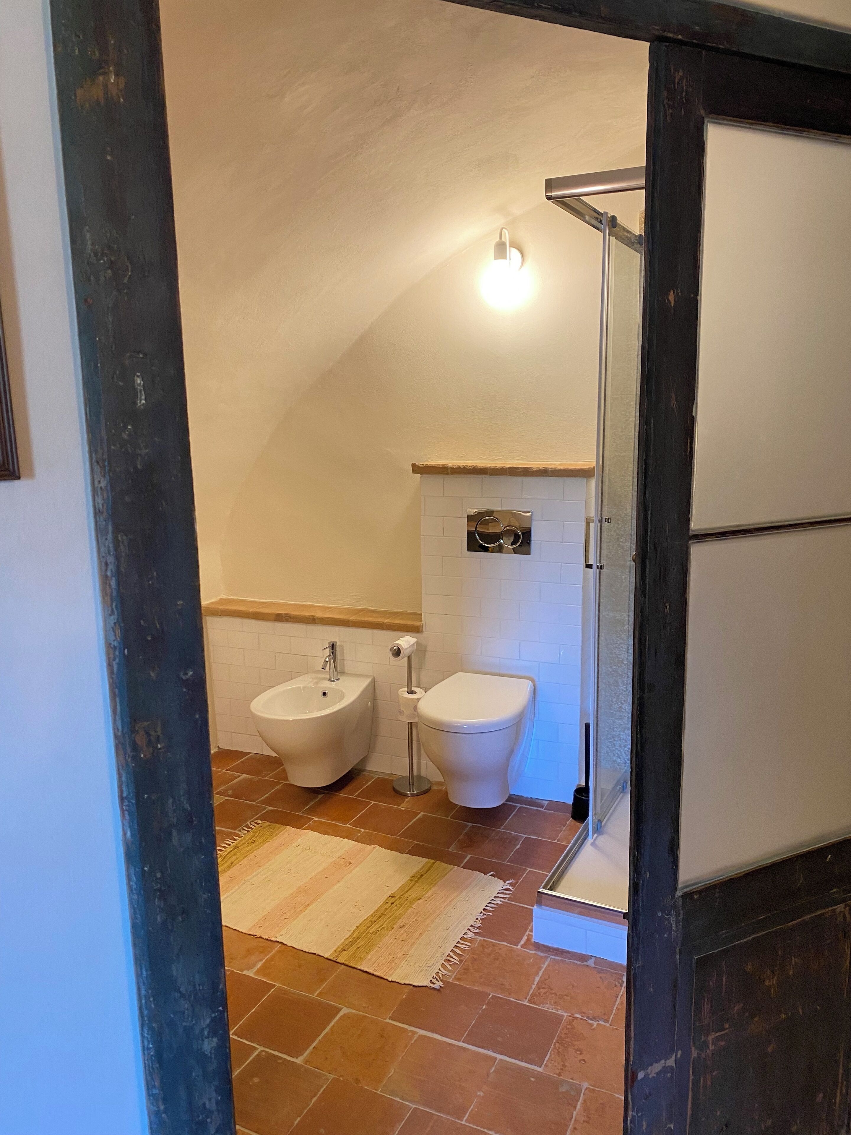 A bathroom with a bidet, toilet, and a towel rack.