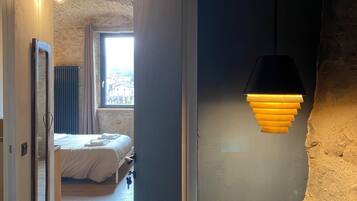 Une chambre moderne avec un mur en pierre, un lit et une lampe suspendue.