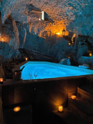 Un espace de détente avec un jacuzzi, des bougies et un mur en pierre.