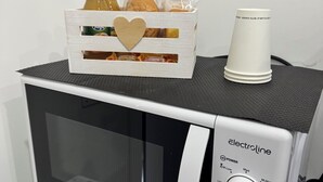 A microwave oven with a wooden crate containing food items and a disposable cup on top. - Apartment San Vitaliano-Naples (San Vitaliano)