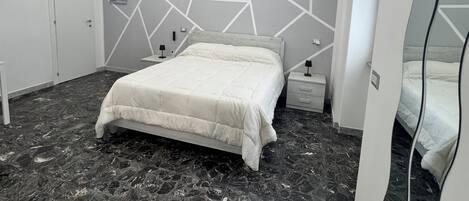 A modern bedroom with a bed, nightstands, and a marble floor.