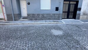 A building with a grey facade, a white door, a window with blinds, and a black gate. - Apartment San Vitaliano-Naples (San Vitaliano)