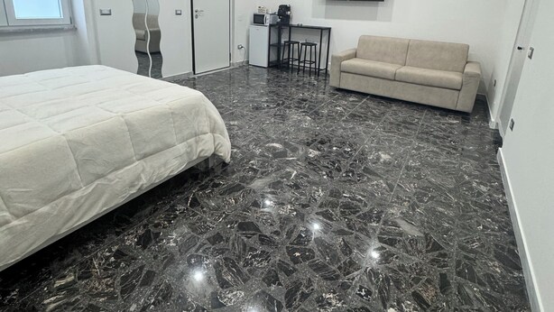 A modern bedroom with a large bed, a sofa, a TV, and a small kitchenette. - Apartment San Vitaliano-Naples (San Vitaliano)
