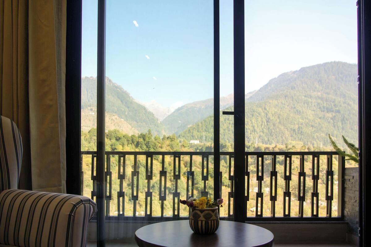 A room with a view of mountains through a balcony with a patterned railing.