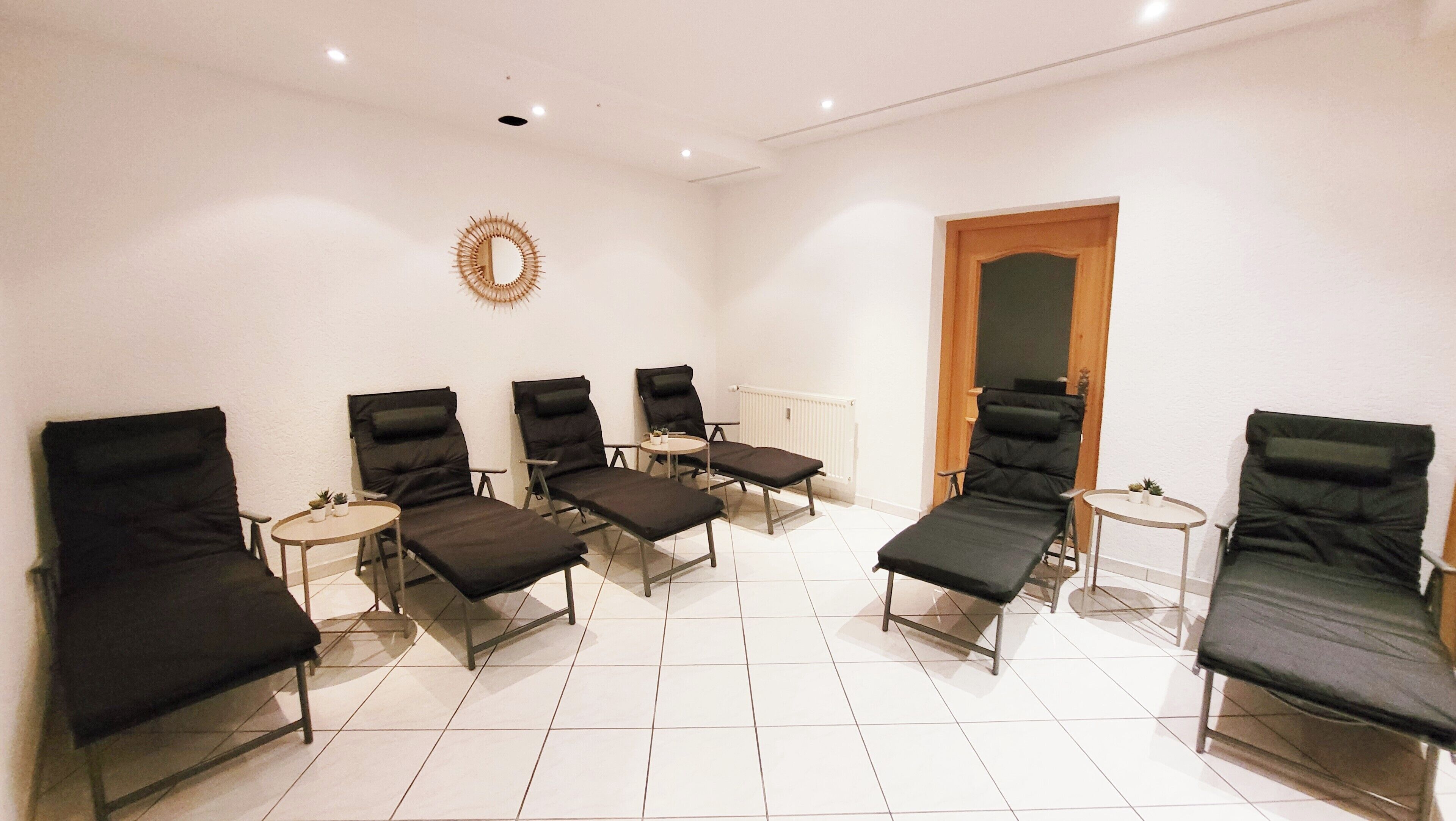 A room with six reclining chairs arranged around a central table, a radiator, and a door.