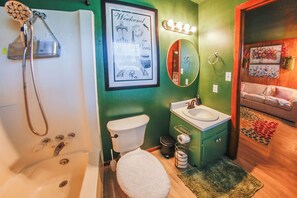Une salle de bain équipée d’une baignoire, de toilettes, d’un lavabo et d’un tableau encadré représentant la Tour Eiffel.