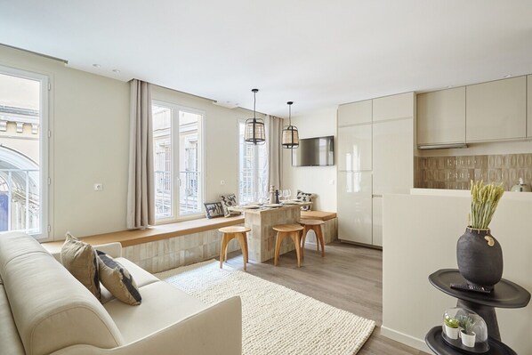 Una cocina moderna con comedor, ventanas amplias y una sala de estar con sofá y mesa de centro.