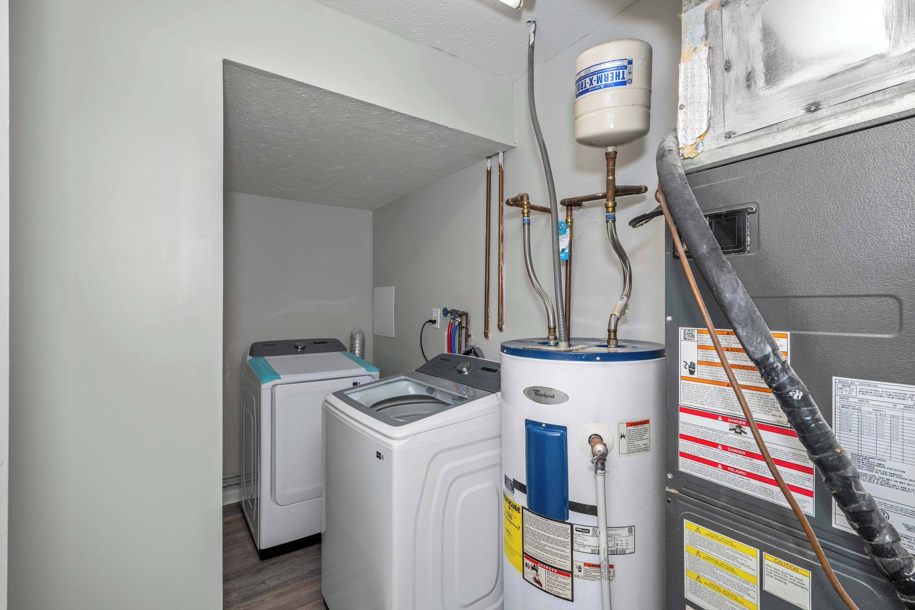A laundry room with two washing machines and a water heater.