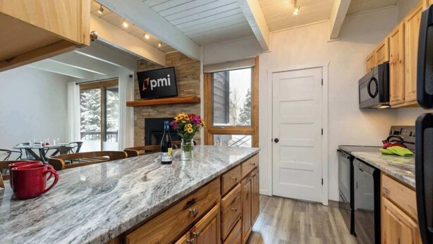 A modern kitchen with wooden cabinets, a marble countertop, and a built-in microwave.