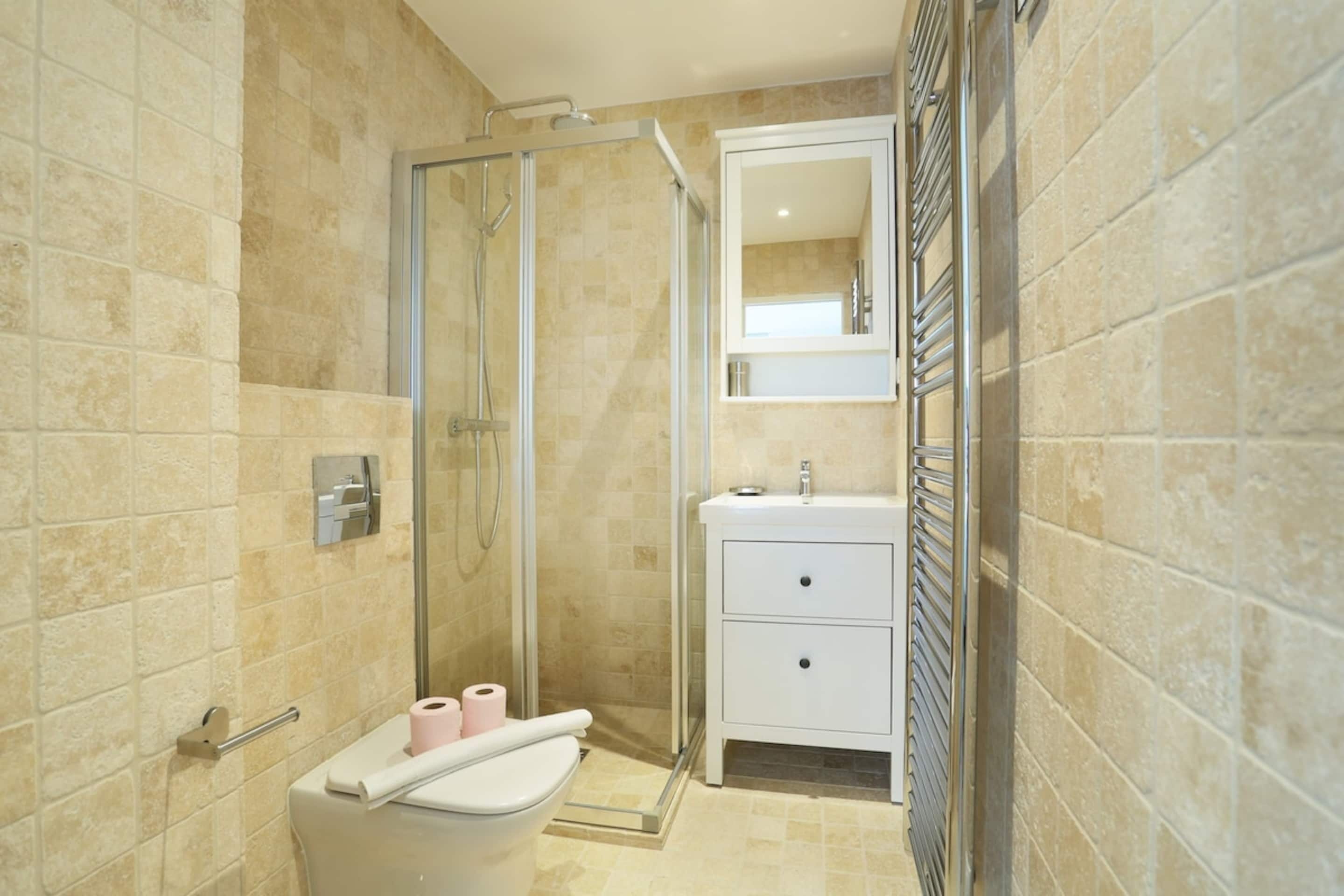 Une salle de bain avec une douche à parois de verre, un lavabo blanc et un miroir au-dessus du lavabo.