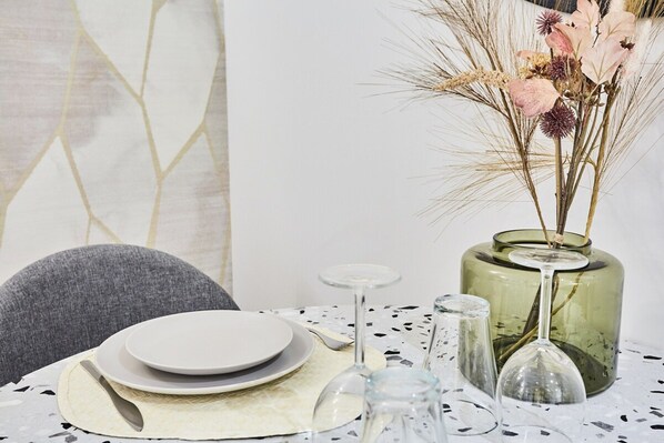 A dining table set with plates, a glass, and a vase with dried flowers.