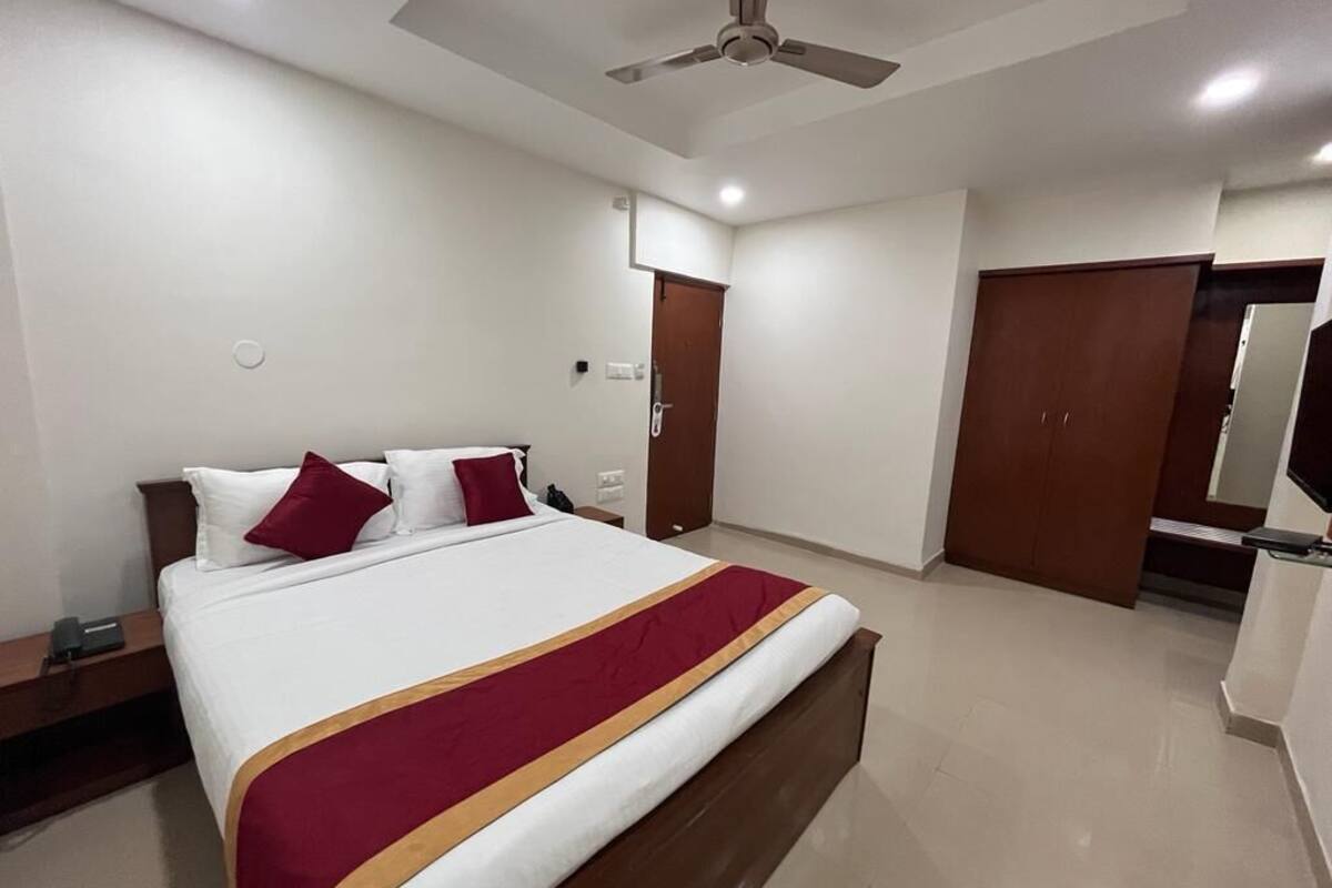 A hotel room with a large bed, a ceiling fan, a wardrobe, and a bathroom with a mirror.