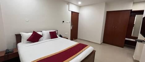 Une chambre d’hôtel avec un grand lit, un ventilateur de plafond, une armoire et une salle de bain avec un miroir.
