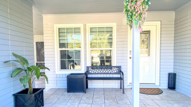 A covered porch with a bench, a potted plant, and a door with a glass panel. - Great place to meet up (Gainesville)