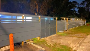 A row of grey utility buildings with illuminated windows, surrounded by trees and a grassy area. - Great place to meet up (Gainesville)