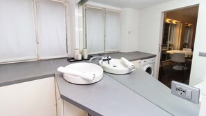 A modern bathroom with a double sink, a washing machine, and a shower area. - Charming Studio Paris / Le Marais (Paris)
