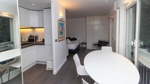 A modern, compact hotel room with a kitchenette, a dining area, and a bed. - Charming Studio Paris / Le Marais (Paris)