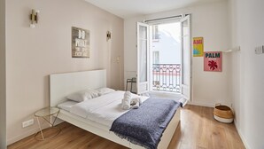 A bedroom with a bed, a small bedside table, a window with a view, and a wall with a sign. - Apartment Paris Exposition Park Center (Paris)