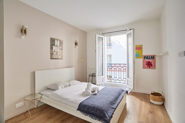Une chambre à coucher avec un lit, une petite table de chevet, une fenêtre donnant sur un paysage agréable et un mur orné d’une inscription.