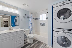 Bathroom features a white sink, toilet, and bathtub, along with two washing machines.