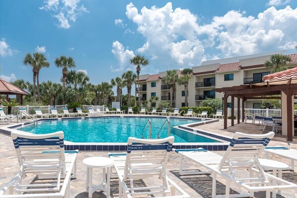 Relax by the pool surrounded by palm trees and lounge chairs.