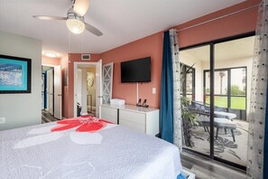Relax in comfort with a large bed, ceiling fan, and flat-screen TV, plus a patio area with outdoor seating.