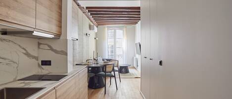 Een moderne keuken met houten kastjes, een marmeren spatwand en een eethoek met een tafel en stoelen.
